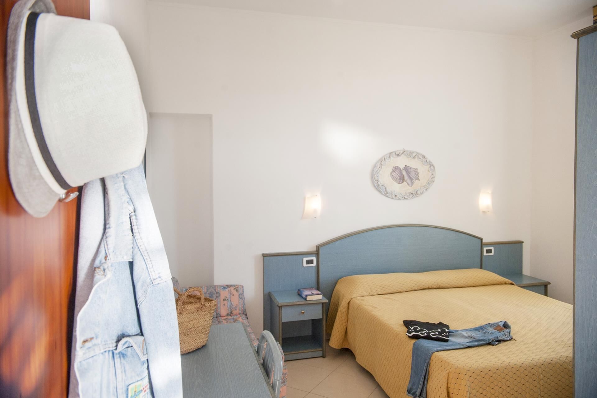 Un dormitorio con cama, mesitas de noche, una lámpara de pared y un plato decorativo.