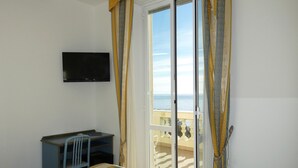 Quarto com cama, escrivaninha, televisão e varanda com vista.