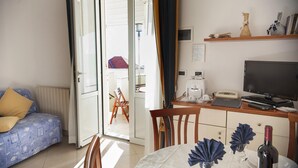 Quarto com cama, escrivaninha com computador, televisão e mesa de jantar posta para dois.