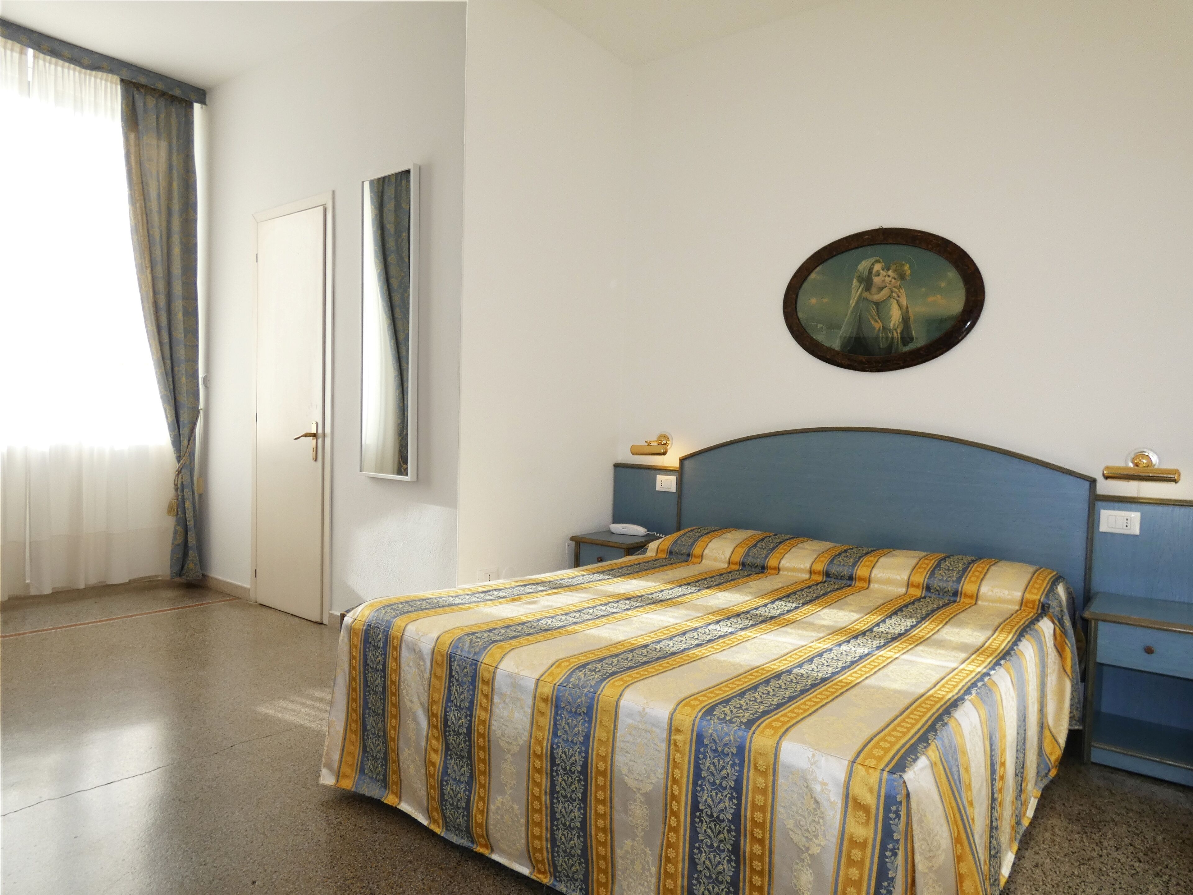 Una camera da letto con un letto, un comodino, uno specchio e un quadro appeso al muro.