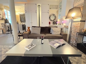 A modern living room with a sofa, a coffee table, and a fireplace. - Le Loft Villehardouin (Paris 03)