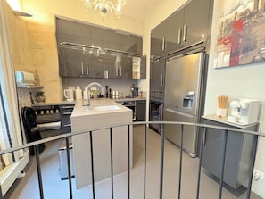 A modern kitchen with stainless steel appliances, a central island, and a small coffee station. - Le Loft Villehardouin (Paris 03)