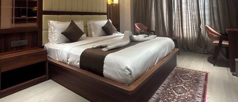 A modern hotel room with a large bed, a desk, and a chair.
