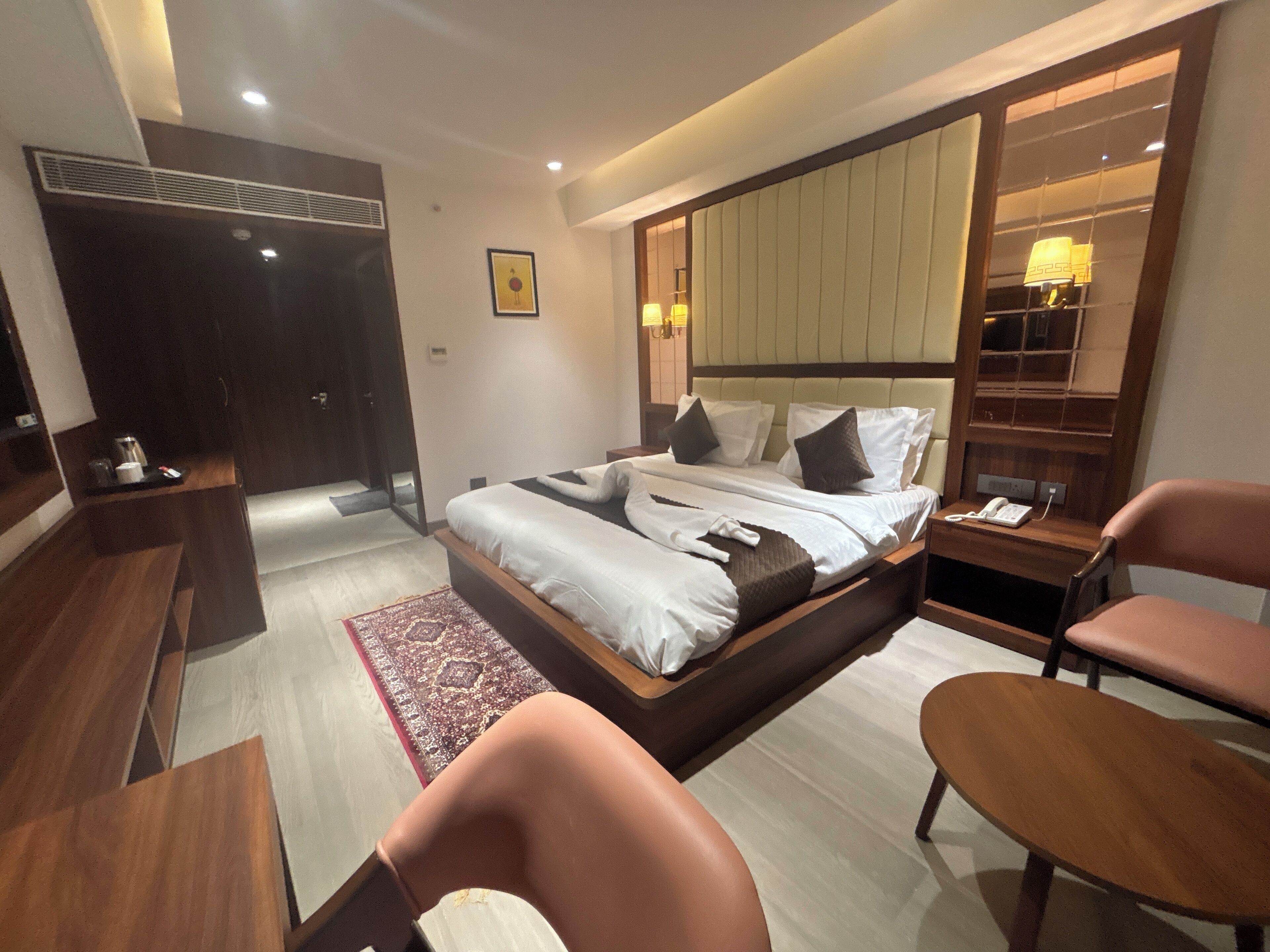 Una habitación de hotel moderna con una cama grande, un escritorio, una silla y un armario.