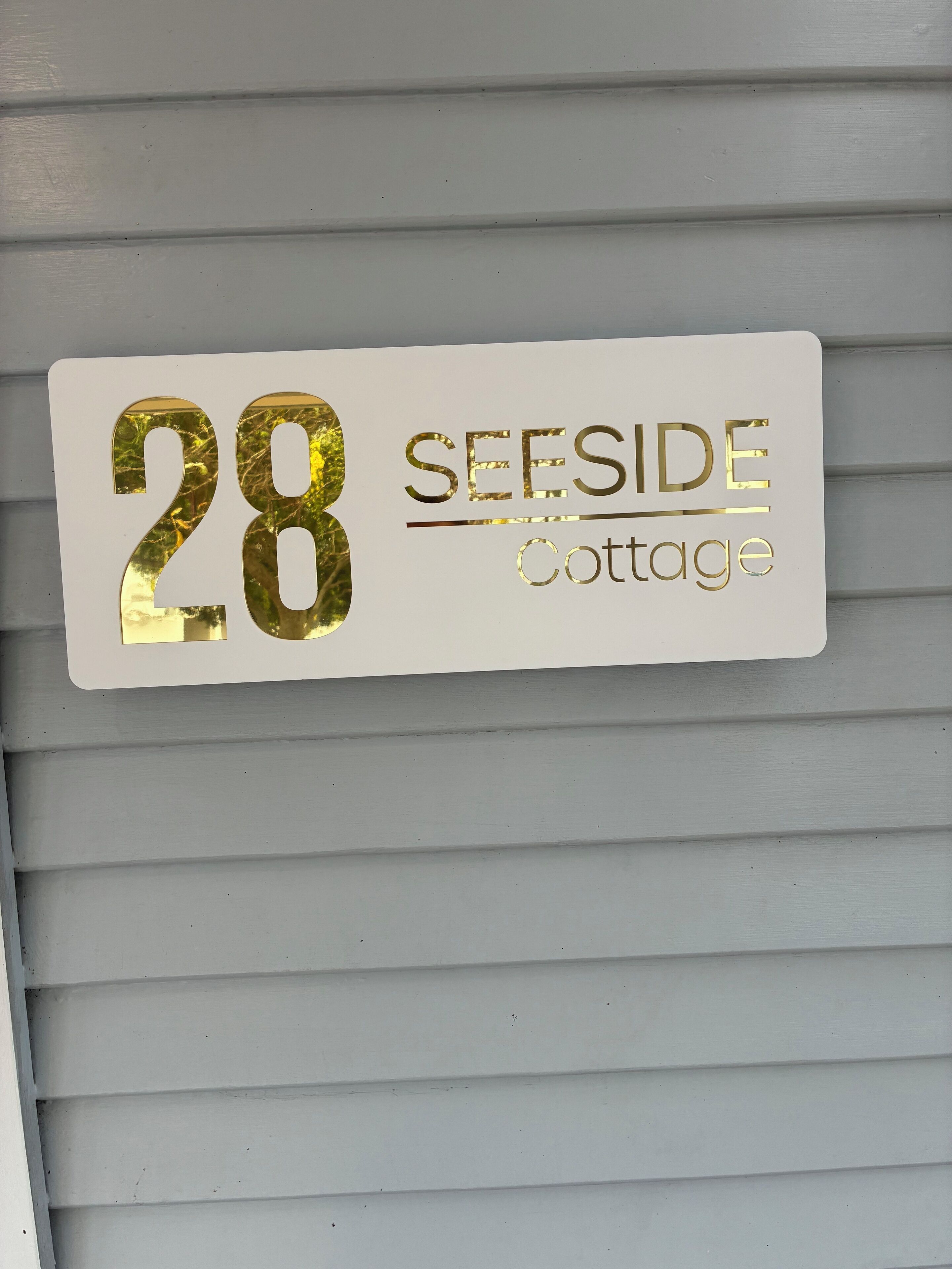 Une plaque de numéro de maison portant l’inscription « 28, Cottage Seaside ».