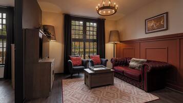 A room with a fireplace, two armchairs, a sofa, a coffee table, and a chandelier.