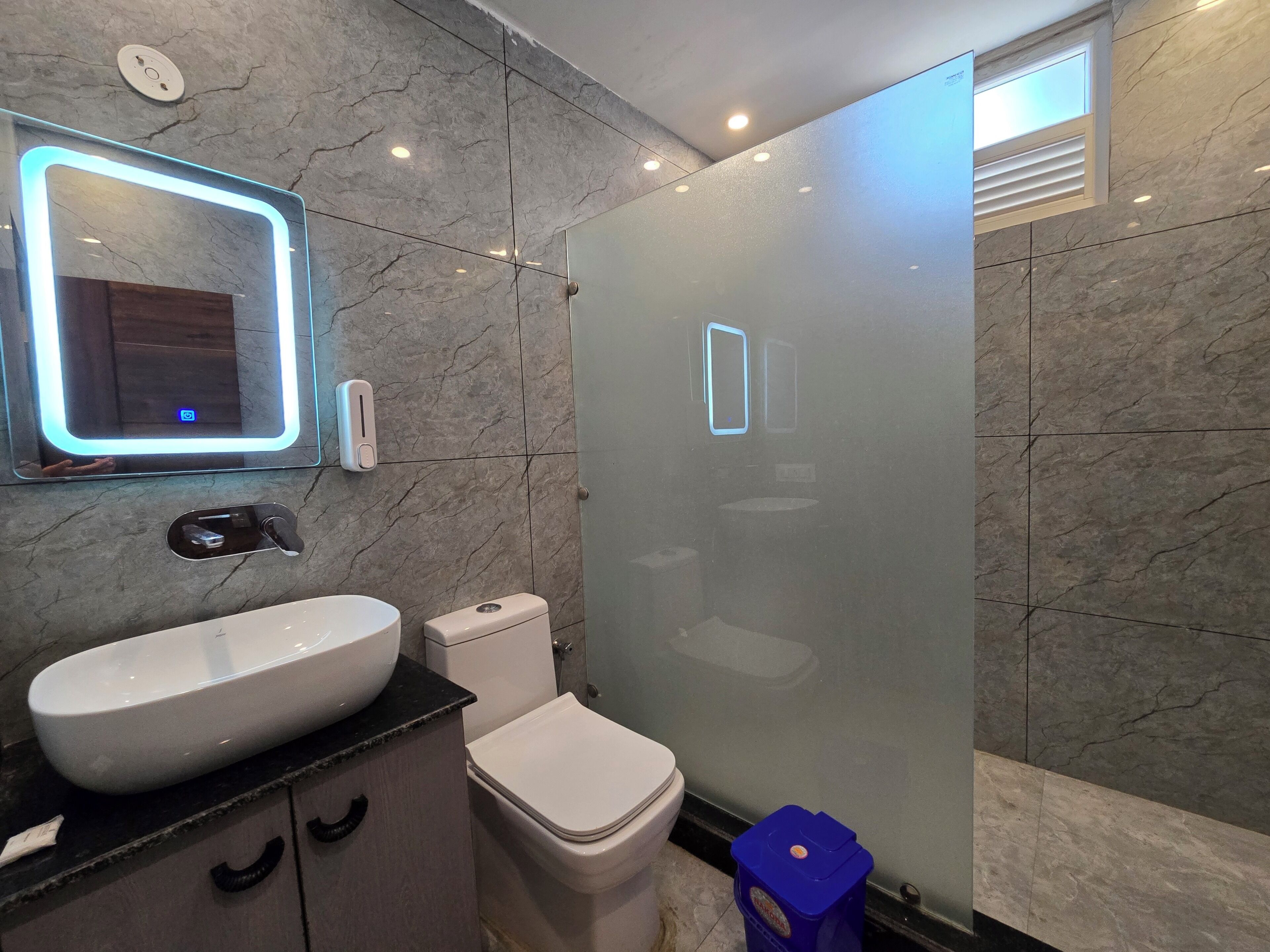 A modern bathroom with a large mirror, a toilet, and a sink.