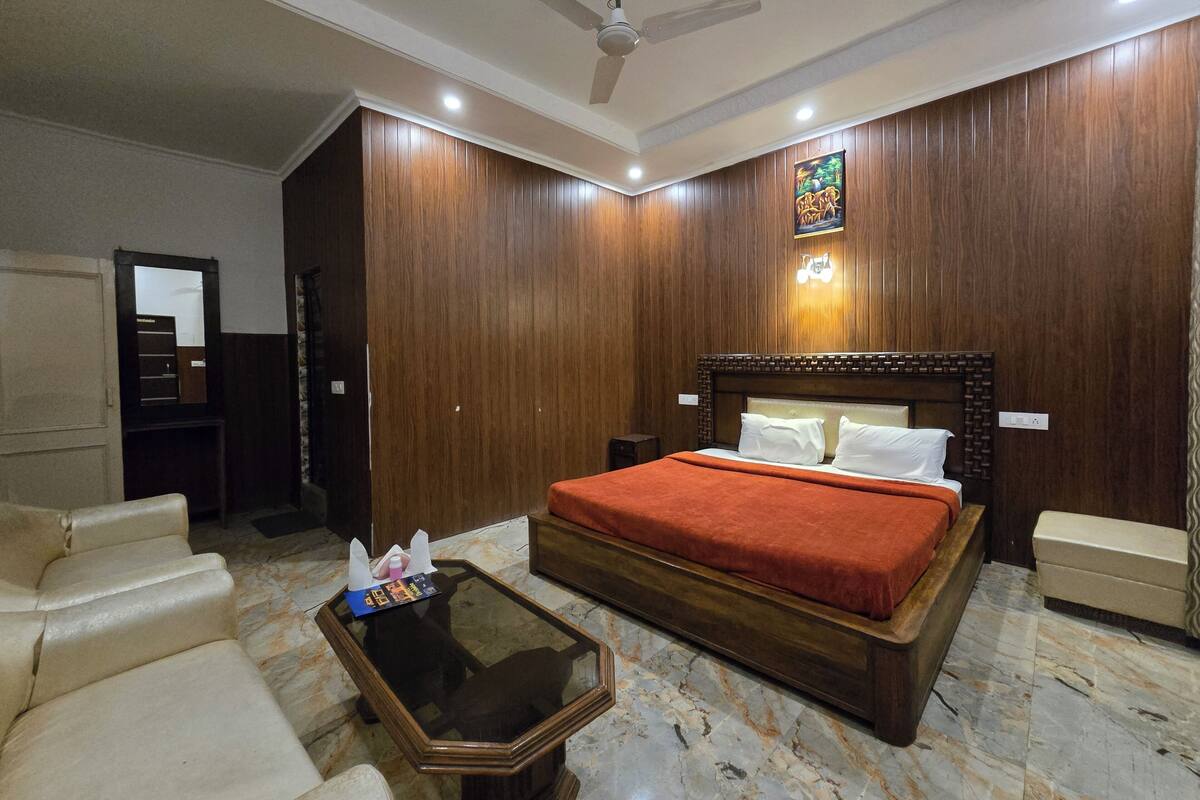 A hotel room with a large bed, a glass coffee table, a sofa, and a ceiling fan.