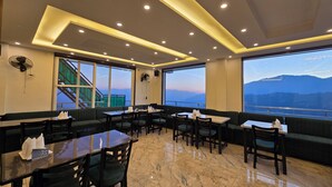A restaurant with a terrace view, marble flooring, and modern lighting. - Hotel Divshikha (Kasauli)