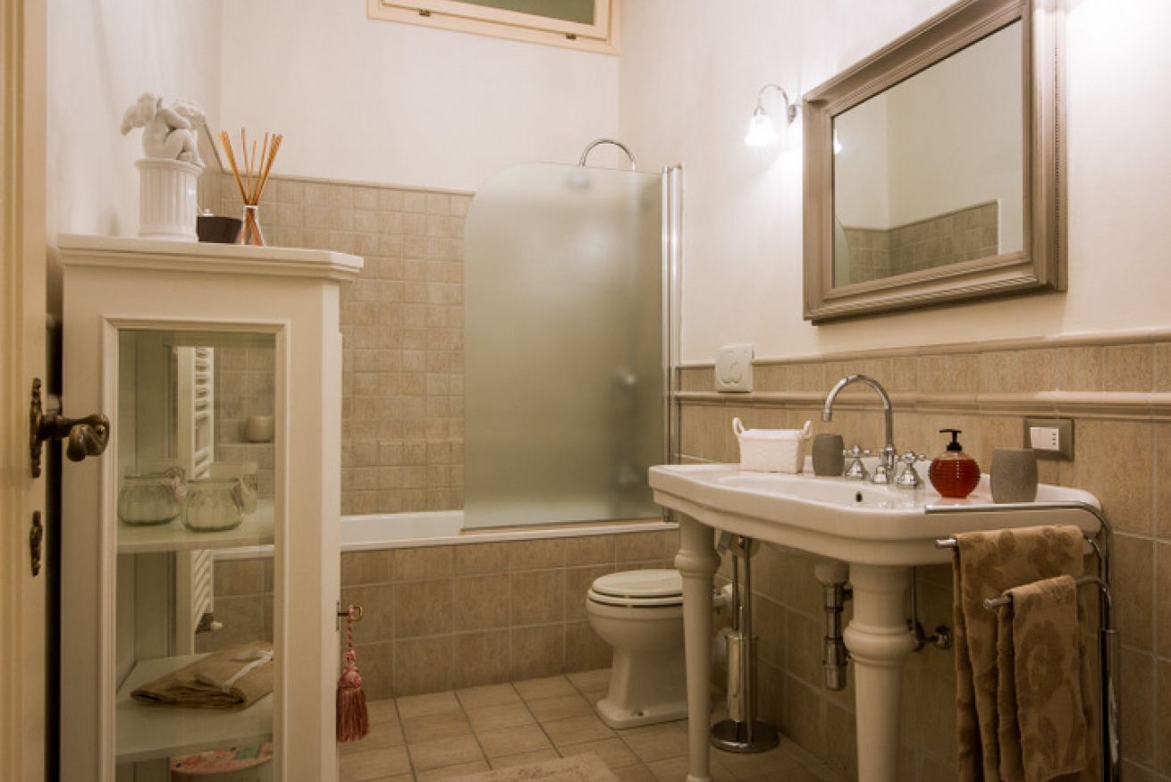 A bathroom with a toilet, a sink, a mirror, and a shower.
