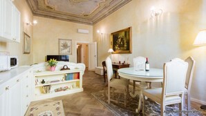Un comedor con una mesa redonda, sillas, una estantería y un techo con molduras decorativas.