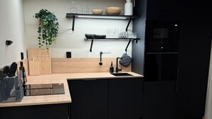 A modern kitchen with a central island, black cabinetry, a wooden countertop, and a built-in oven. - Adorable 2-bedroom apartment in Telemark (Telemark)