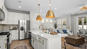 A modern kitchen with white cabinetry, stainless steel appliances, and pendant lighting. - Luxury New Build in Cherry Grove - Beach and Golf Destination (North Myrtle Beach)