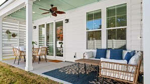 A covered patio with a ceiling fan, wicker furniture, and a blue patterned rug. - Luxury New Build in Cherry Grove - Beach and Golf Destination (North Myrtle Beach)