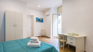 A bedroom with a bed, a desk, and a chair. - Muzy Flat at Capuana by Napoliapartments (Naples)