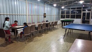 A room with a ping pong table, chairs, and a dartboard. - Vertical Valley Resort (Kalsi)