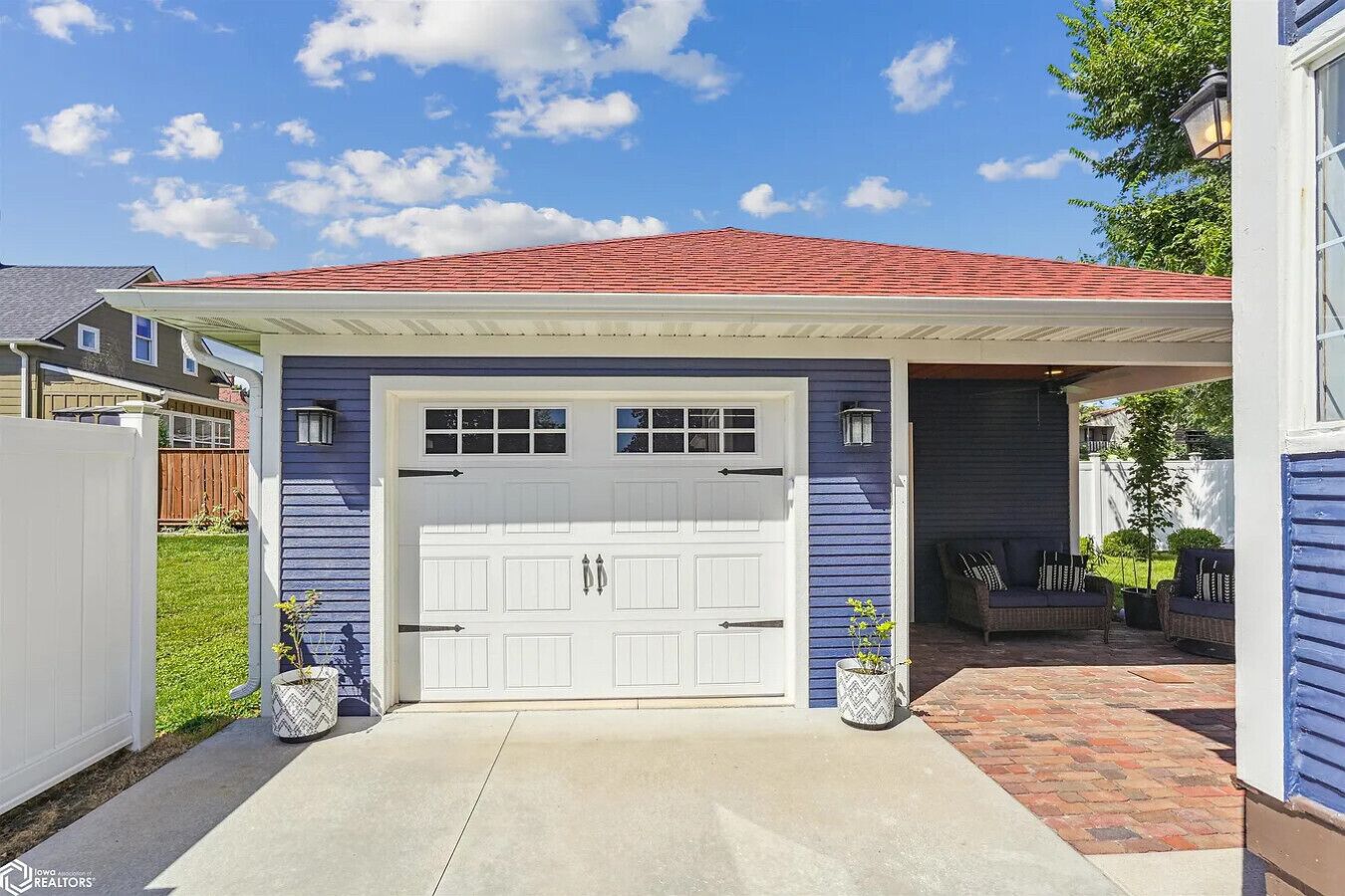 A two-car garage with a covered entryway, a red roof, and a blue exterior wall.