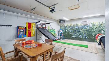 Een kamer met een basketbalring, een dartbord en een muurschildering.