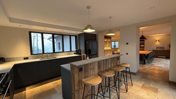 Una cocina moderna con una isla central, taburetes de bar y una zona de comedor con vistas.