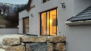 Una casa moderna con cimientos de piedra, ventanas amplias y un interior luminoso.