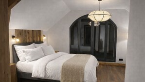Un dormitorio con cama, cabecero de madera y lámpara colgante.