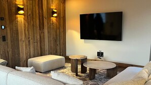 Una sala de estar moderna con un sofá modular, un televisor de pantalla plana y una pared de acento de madera.