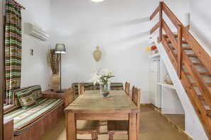 A dining area with a wooden table, benches, and a vase of flowers. - Holiday Home 'Miguelin 2' with Shared Pool, Wi-Fi and Air Conditioning (Zahora)