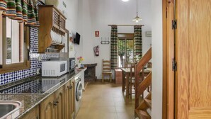 A kitchen with a microwave, sink, and wooden cabinets. There is a staircase leading to another room. - Holiday Home 'Miguelin 2' with Shared Pool, Wi-Fi and Air Conditioning (Zahora)