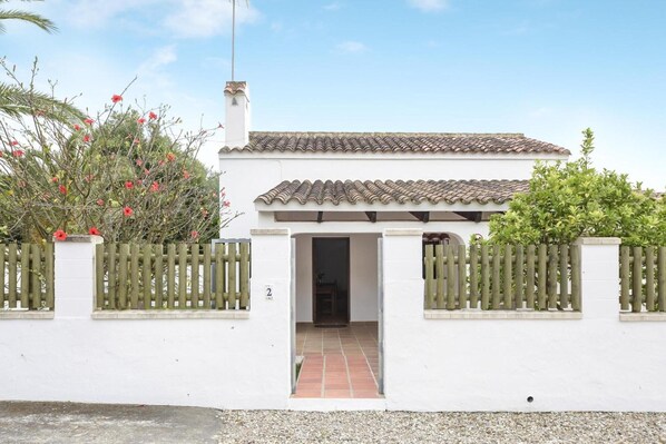 A white building with a tiled roof, a wooden gate, and a number '2' on the wall. - Holiday Home 'Miguelin 2' with Shared Pool, Wi-Fi and Air Conditioning (Zahora)