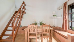 A wooden staircase, a dining table with chairs, and a window with curtains. - Holiday Home 'Miguelin 1' with Shared Pool, Wi-Fi and Air Conditioning (Zahora)