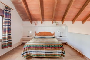 A bedroom with a wooden ceiling, a bed with a striped bedspread, bedside lamps, and a window with a curtain. - Holiday Home 'Miguelin 4' with Shared Pool, Wi-Fi and Air Conditioning (Zahora)
