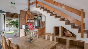Eine Holztreppe führt zu einer oberen Ebene, einem Essbereich mit Tisch und St ühlen sowie einer Küchenzeile mit Mikrowelle und Schränken.