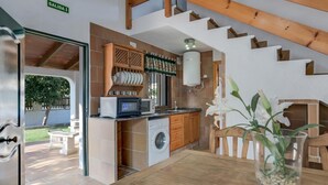 A compact kitchen with a washing machine, microwave, and a small dining area with a table and chairs. - Holiday Home 'Miguelin 8' with Shared Pool, Wi-Fi and Air Conditioning (Zahora)