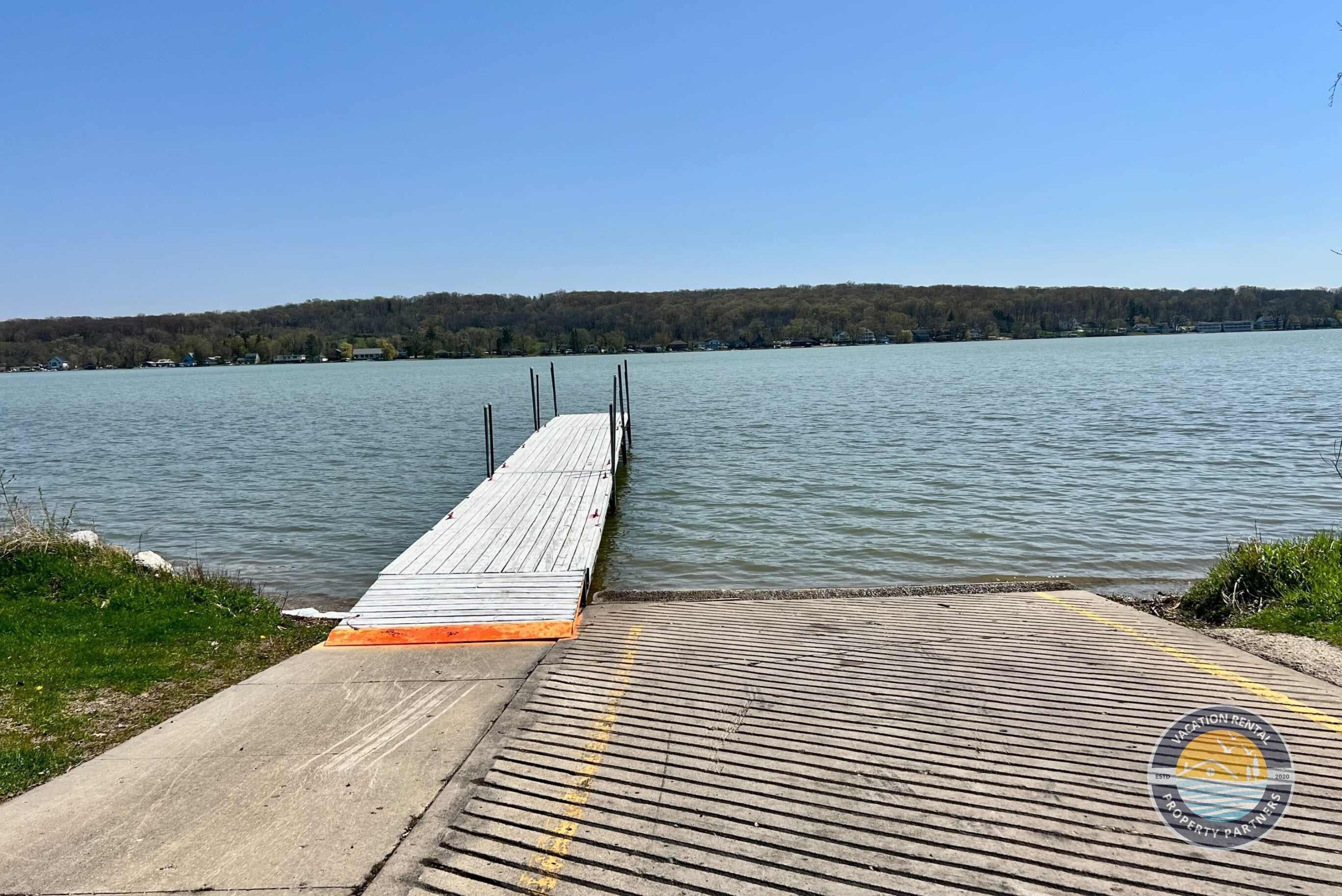 A wooden dock extending into a calm lake with a clear sky above.