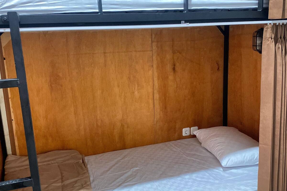 Une chambre avec des lits superposés, des murs en bois et un sol carrelé.