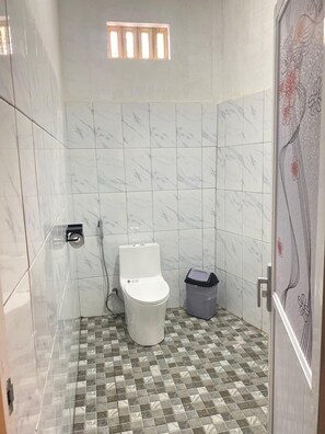 Ein Badezimmer mit Toilette, Dusche und Mülleimer.
