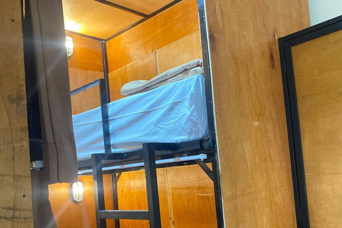 Une chambre avec un lit superposé, des murs en bois et une échelle.