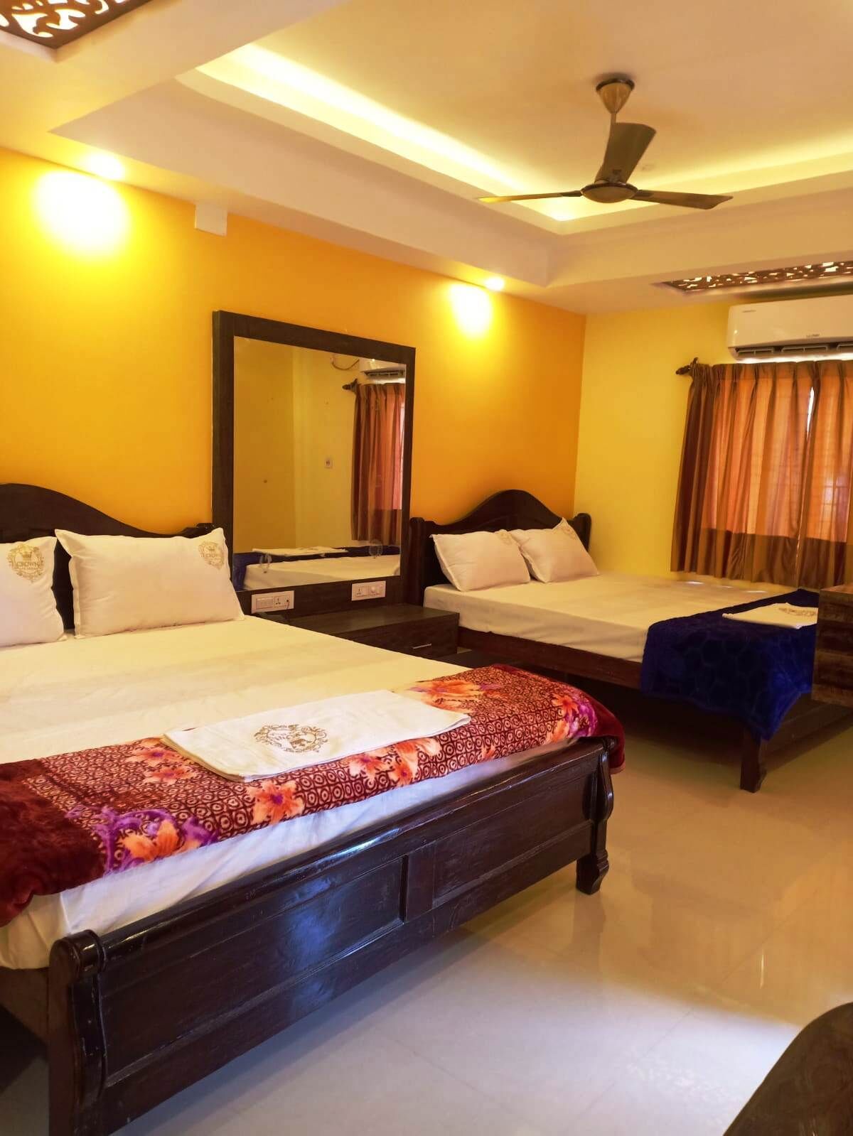 A hotel room with two beds, a ceiling fan, and an air conditioning unit.