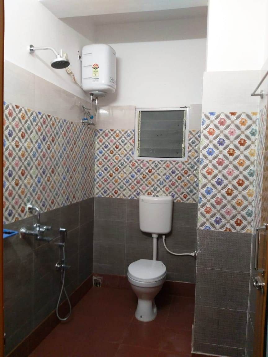 A small bathroom with a toilet, a shower, and a water heater.
