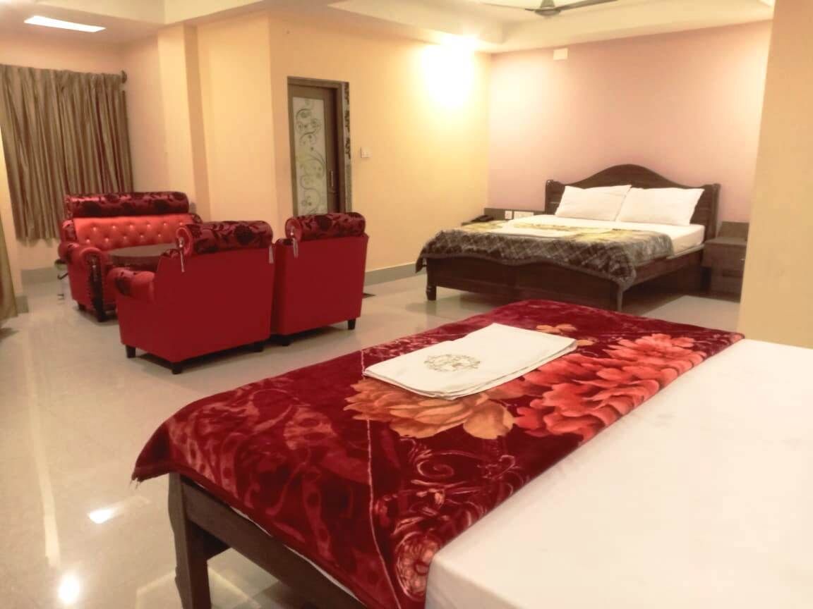 Habitación de hotel con cama, sofá rojo y zona de estar separada.