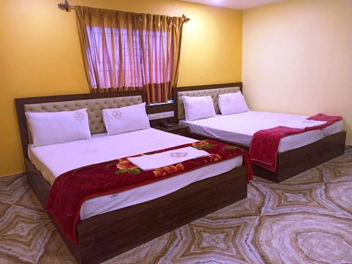 Habitación de hotel con dos camas, cada una con cabecera de madera, ropa de cama blanca y una manta roja.
