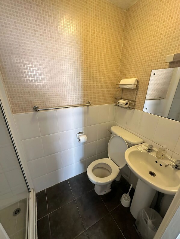 A small bathroom with a toilet, sink, and a mirror. - Granby Hotel (Scarborough)