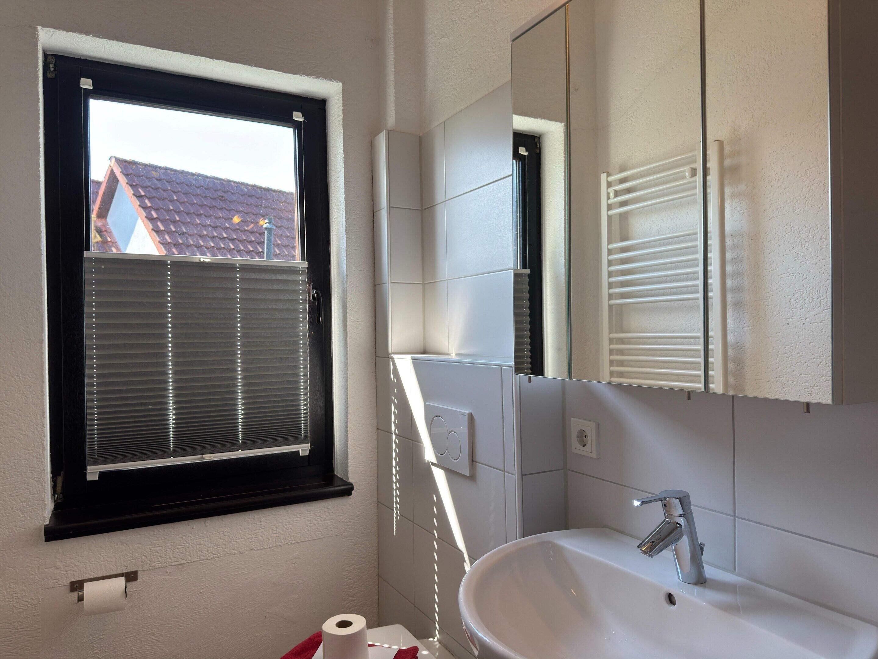 Ein Badezimmer mit Fenster, Waschbecken und Spiegel.