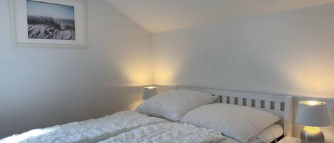 Une chambre à coucher avec un lit, deux lampes de chevet, une table de chevet et un tableau encadré au mur.