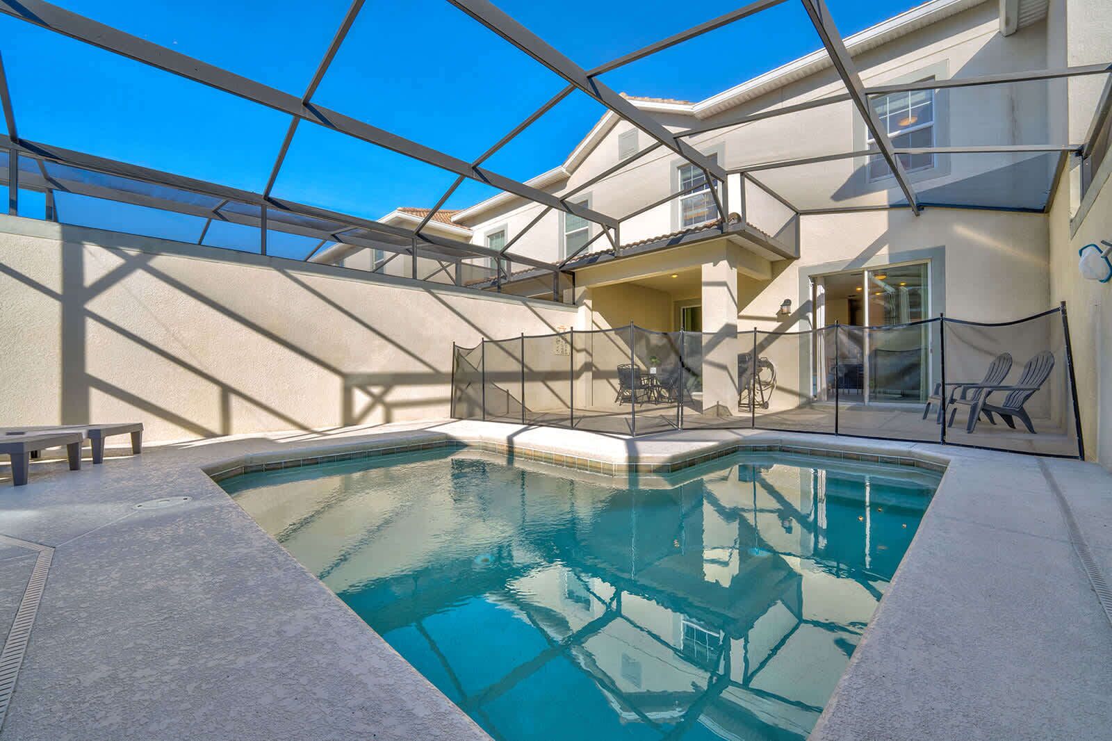 A swimming pool with a glass ceiling, surrounded by a white building with a balcony and outdoor seating.