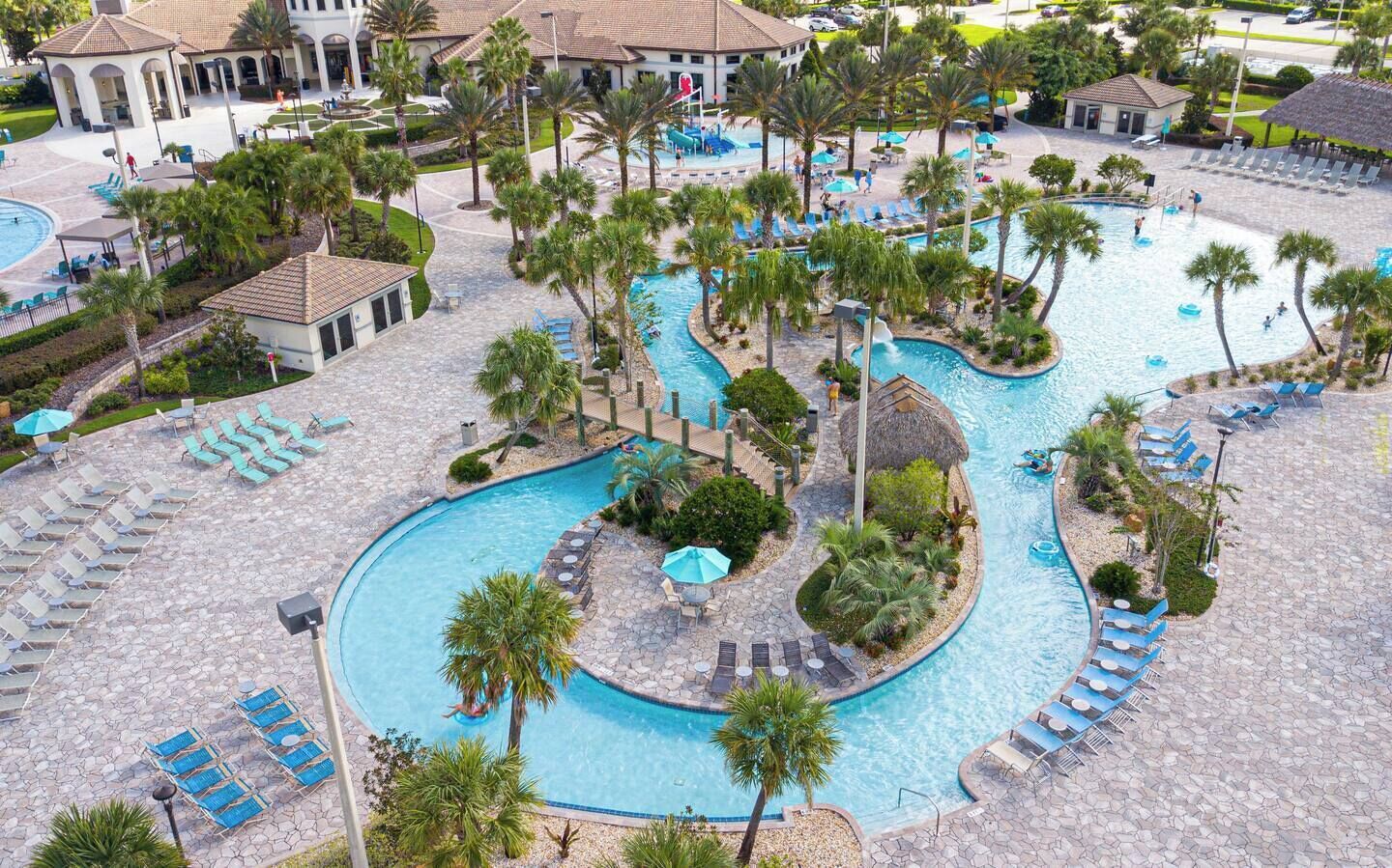 Resort pool area featuring a winding lazy river surrounded by palm trees and lounge chairs.
