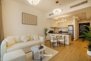 Ein modernes Wohnzimmer mit einer Couch, einem Couchtisch und einem Essbereich mit Stühlen sowie einer Küche im Hintergrund.