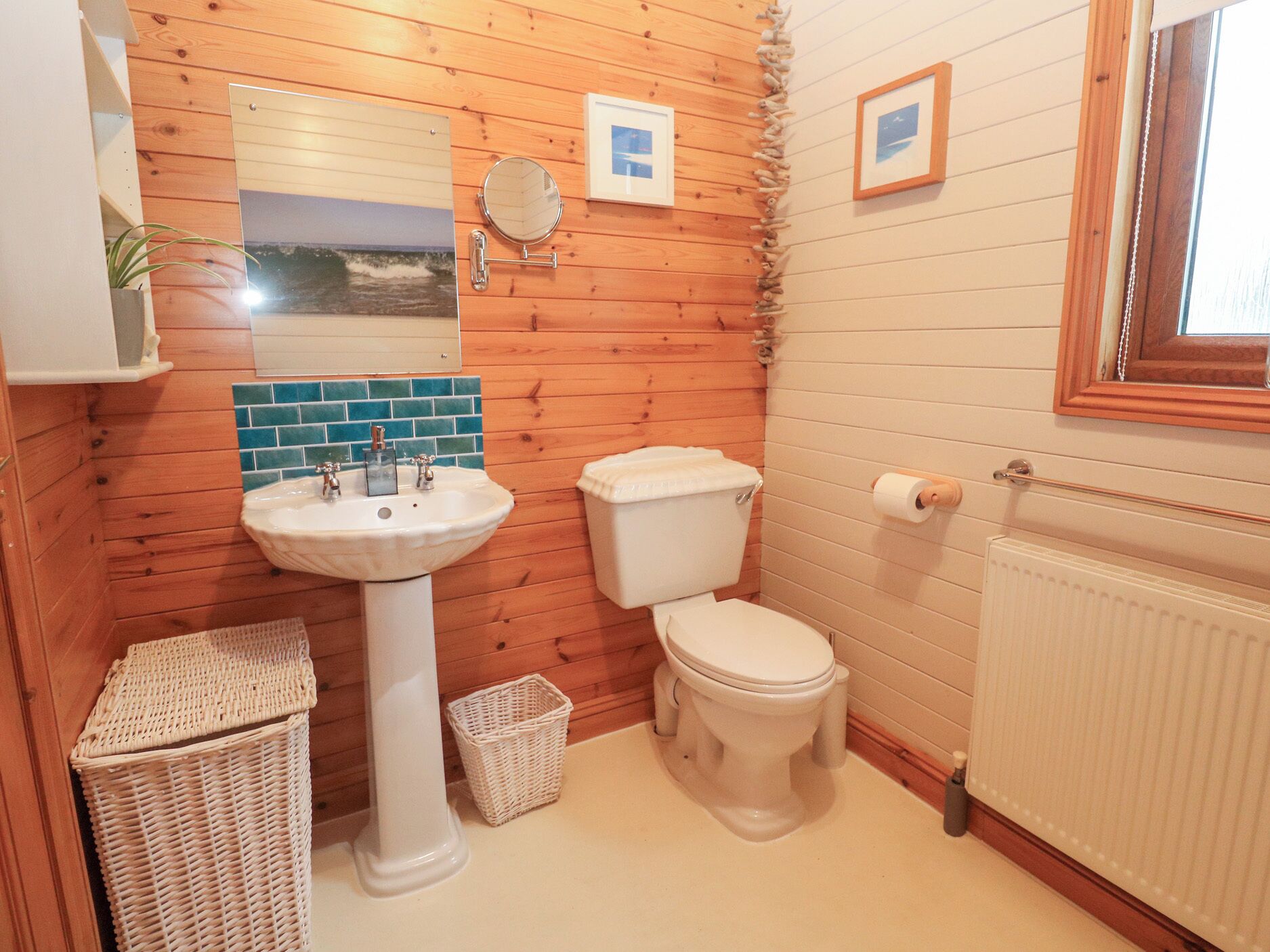 A bathroom with wooden walls, a white sink, a toilet, and a small wicker basket.