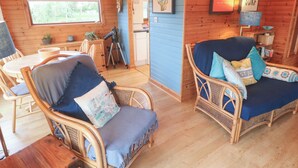 A cozy cabin interior with wicker furniture, a telescope, and framed artwork on the walls. - Lamorna (Penzance)