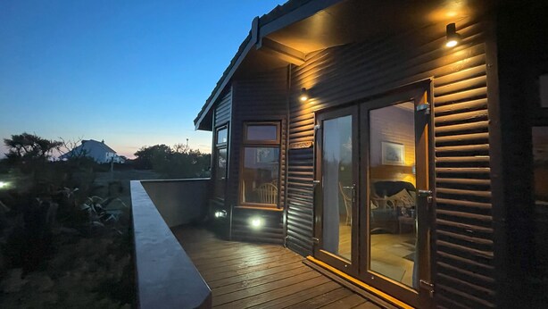 A wooden house with a covered deck and large sliding glass doors. - Lamorna (Penzance)